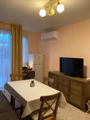 a living room with a table and a flat screen tv at Mirabell Apartment Bansko - Mountain View & Fireplace in Bansko