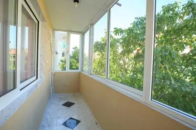 an empty room with windows with a view of trees at Мария Парк in Sandanski