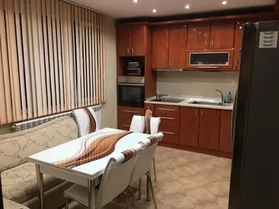 a kitchen with wooden cabinets and a table and chairs at Мария Парк in Sandanski