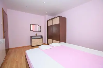 a bedroom with a large white bed and a tv at Мария Парк in Sandanski