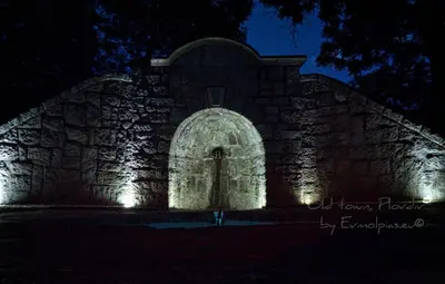 a stone building with a door at night at Art apartment EVMOLPIAS near Roman stadium in Plovdiv