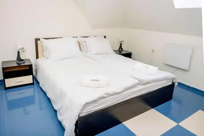 a bedroom with a large bed with white sheets at Villa Kalina Apartments in Bansko