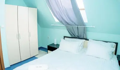 a bedroom with a white bed and a window at Villa Kalina Apartments in Bansko