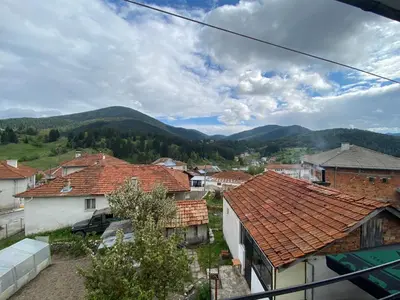 a town with houses and mountains in the background at Къща за гости 