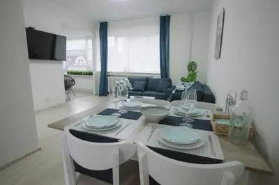 a dining room table with white chairs and a living room at Landmark Apartment in Sofia