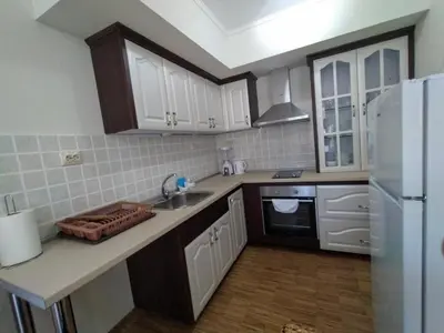 a kitchen with white cabinets and a sink and a refrigerator at Вила Магдалена, к-с Александриа in Dobrinishte
