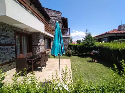 a patio with a table and a blue umbrella at Вила Магдалена, к-с Александриа in Dobrinishte