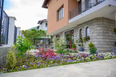 a garden in front of a building with flowers at Вила Влахов in Sapareva Banya