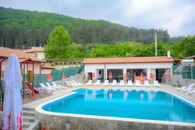 a large swimming pool with chairs and a building at Вила Влахов in Sapareva Banya