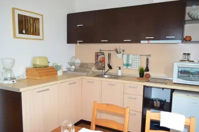 a kitchen with white cabinets and a table and a microwave at Cozy studio in 