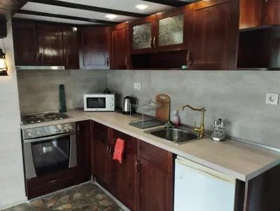 a kitchen with wooden cabinets and a sink and a microwave at Семейна къща Лазарови in Sapareva Banya