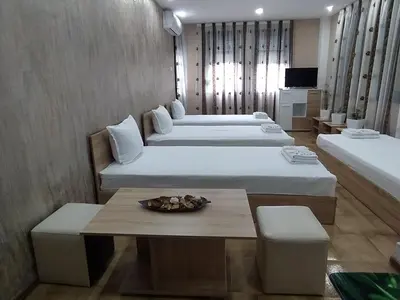 a hotel room with two beds and a table at Каламанди in Asenovgrad