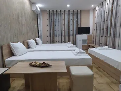 a hotel room with two beds and a table at Каламанди in Asenovgrad