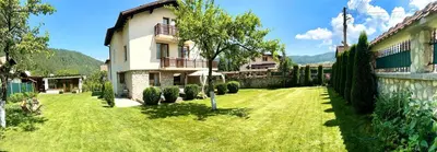 a green yard with a building and a house at Villa Rila Garden in Beli Iskar