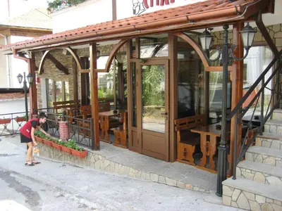 a woman standing in front of a building with glass doors at Spartak Family Hotel in Smolyan