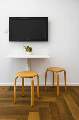 a table with two stools and a tv on a wall at North Panoramic Apartment in the art district of Kapana in Plovdiv