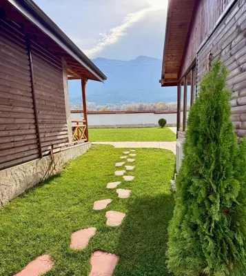 a walkway next to a building with a tree at Къщи за гости “Планински Рай” Mountain Paradise in Resilovo