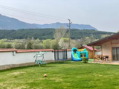 a yard with a house with a playground at Къщи за гости “Планински Рай” Mountain Paradise in Resilovo