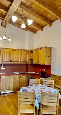 a kitchen with a table and chairs and wooden cabinets at Pirin Golf Hotel Private Apartments Апартаменти Планински Изгрев в Пирин Голф in Razlog
