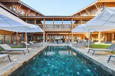 a swimming pool with chairs and umbrellas in front of a building at Pirin Golf Hotel Private Apartments Апартаменти Планински Изгрев в Пирин Голф in Razlog