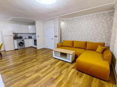a living room with a yellow couch and a kitchen at Sofia hotel apartments in Sofia