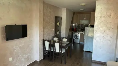 a kitchen with a table and chairs and a television on a wall at Thea Apart in Sandanski