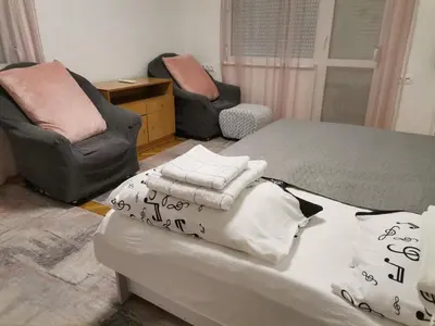 a bedroom with a bed with pillows and two chairs at Brand New Apartment in Sofia