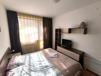 a small bedroom with a bed and a television at Belvedere Holiday Club Private Apartment in Bansko