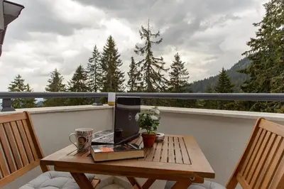 a wooden table with a laptop on a balcony at Luxury 2-bedroom apartment by Studenets Center by Flat Mаnager in Pamporovo