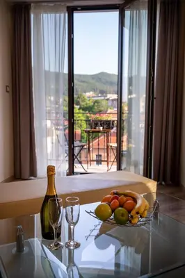a table with a bowl of fruit and a bottle of wine at Family Hotel Konstantinovi in Kyustendil