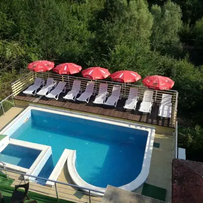 a group of chairs with umbrellas and a swimming pool at Guest House Shipkovo Hills in Shipkovo