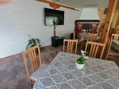 a dining room with a table and chairs and a television at Guest House Shipkovo Hills in Shipkovo