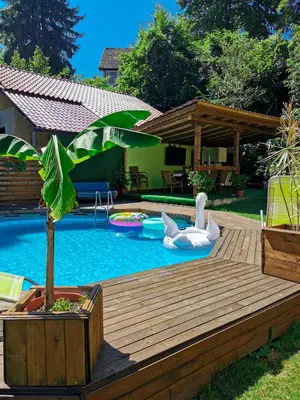 a backyard with a pool with a wooden deck and a swimming pool at Вила Край реката in Botevgrad