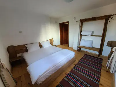 a bedroom with a large white bed and a chair at Вила 111 in Sapareva Banya