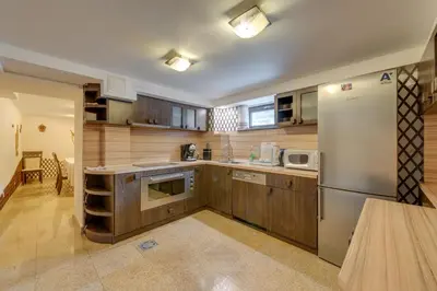 a kitchen with wooden cabinets and a stainless steel refrigerator at Комплекс Орлово гнездо in Beli Iskar