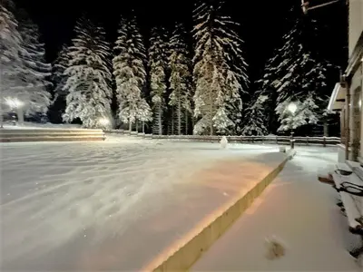 a ice skating rink with snow covered trees at night at Комплекс Орлово гнездо in Beli Iskar