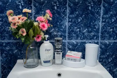 a bathroom sink with a bottle of soap and flowers at Къща за гости Шарон in Petrich