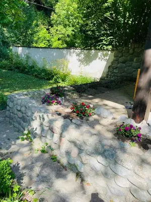 a garden with flowers in a stone wall at Къща за гости Станеви in Ribarica