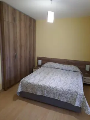 a bedroom with a bed and a large wooden cabinet at Апартамент в MountainLake in Smolyan