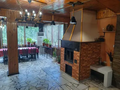 a living room with a fireplace and a dining area at Къща за гости Вишнева градина in Brestnik