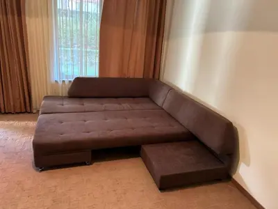 a brown couch sitting in the corner of a room at Bardarova Apartments Downtown Bansko in Bansko