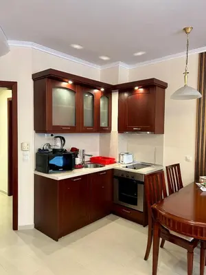 a kitchen with wooden cabinets and a dining room table at Bardarova Apartments Downtown Bansko in Bansko