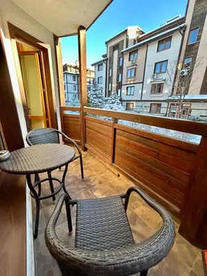 a balcony with two chairs and a table and a window at Bardarova Apartments Downtown Bansko in Bansko