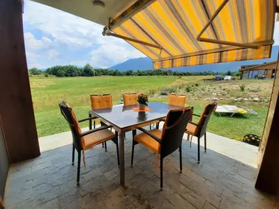 a table and chairs on a patio with a view of a field at Mountain Villa near Bansko in Razlog