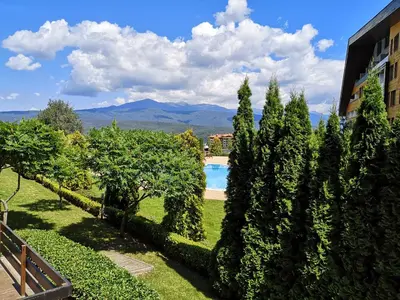 a garden with trees and a swimming pool at Студио за трима, басейн, Aspen Golf Resort, Банско, Разлог in Razlog