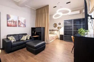 a living room with a black leather couch and a bed at Bohemia - New Apartment with Stylish Design in Sofia