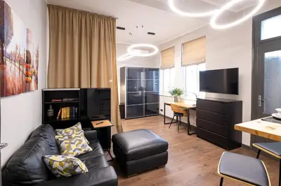 a living room with a black leather couch and a desk at Bohemia - New Apartment with Stylish Design in Sofia