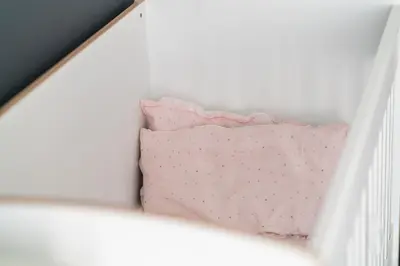 a crib with a pink pillow on top of it at Vertigo Modern 2-Bedroom Apartment with Parking & Vitosha View in Sofia