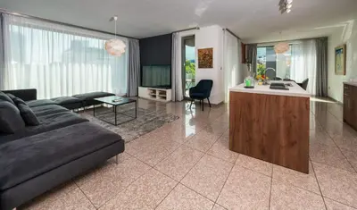 a living room with a couch and a kitchen at Vertigo Modern 2-Bedroom Apartment with Parking & Vitosha View in Sofia
