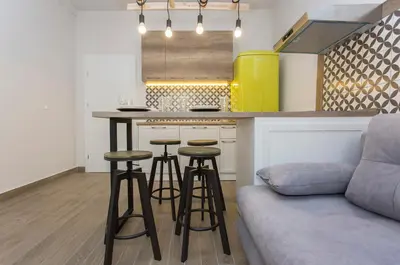 a kitchen with a bar with stools and a couch at Sunny and Modern 1BDR Apartment in the Center in Sofia